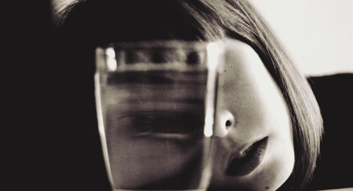 A conceptual sepia-toned portrait featuring a woman and a glass of water with dramatic reflections.