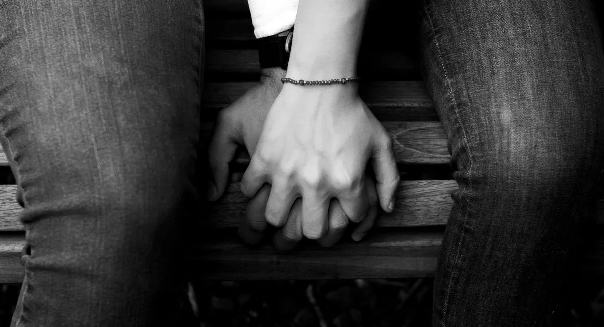 Black and white close-up of a couple holding hands, symbolizing connection and affection.