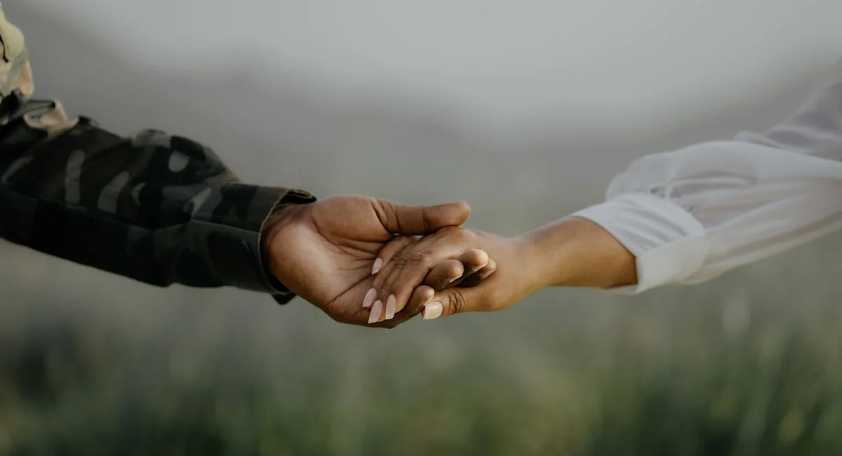 A touching moment of an interracial couple holding hands, signifying love and unity outdoors in Sri Lanka.