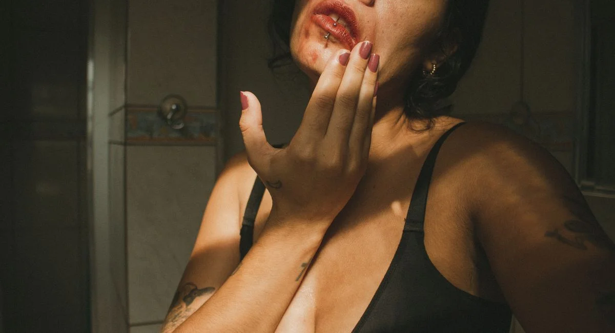 Artistic portrait of a young woman with smudged red lipstick, showcasing emotion and mood in natural light.