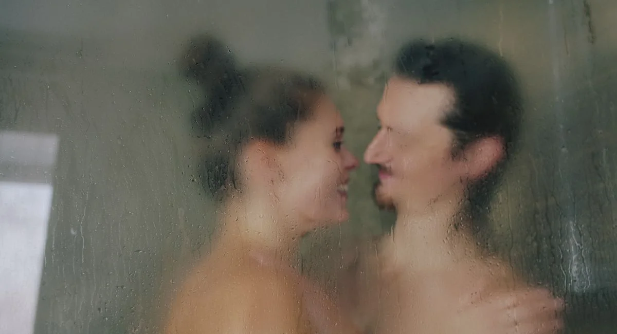 Intimate portrait of a couple behind blurred steamy glass with a romantic ambiance.