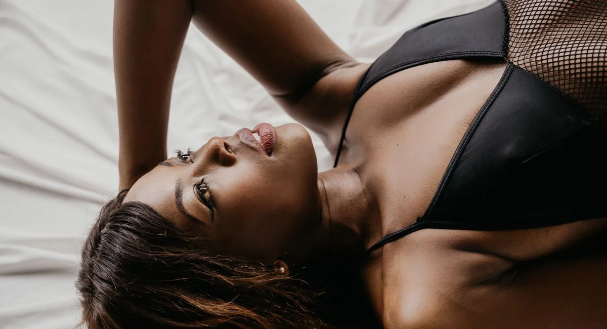 An alluring portrait of a woman in black lingerie lying on a bed.