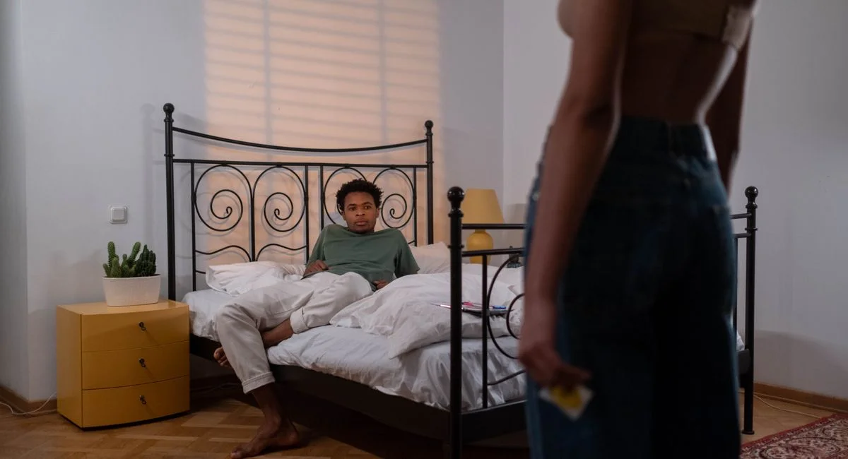 A romantic moment with a couple focusing on safe sex in a cozy bedroom setting.